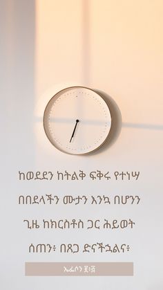 a clock sitting on top of a white table next to a quote from an ethiopian language