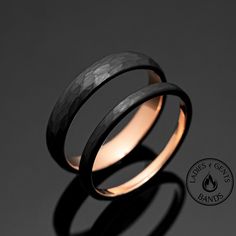 two wedding bands made out of black wood and gold inlays, on a dark background