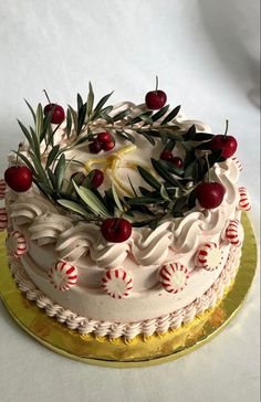 a decorated cake with white frosting and red berries on top, sitting on a gold platter