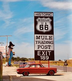 an old red car is parked in front of a sign for the route 66 museum