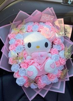 a hello kitty stuffed animal surrounded by pink and white roses in a car seat belt