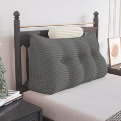 a bed with a pillow on top of it next to a night stand and nightstand