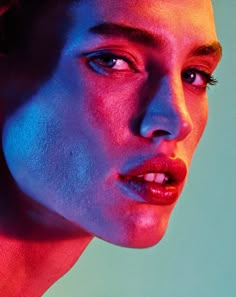 a woman with blue and red light on her face looking at the camera while posing for a photo