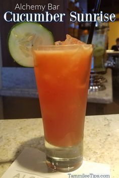 a close up of a drink in a glass with a straw and cucumber on the side