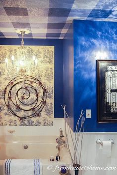 a bathroom decorated in blue and white with an art work on the wall above the bathtub