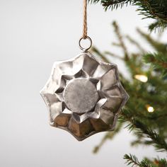 a silver ornament hanging from a christmas tree