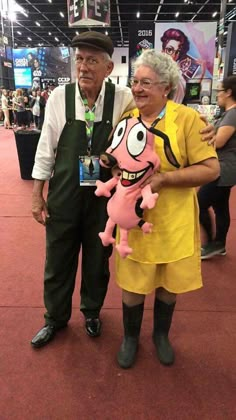 an older man and woman standing next to each other in front of a convention booth