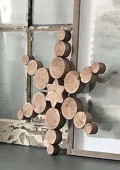 a cross made out of logs sitting next to a window