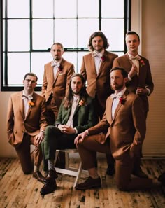 a group of men wearing suits and ties posing for a photo in front of a window