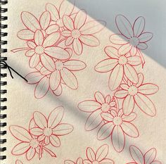 a notebook with red ink on it and flowers drawn on the paper next to it