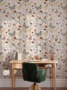 a desk and chair in front of a wallpapered room with flowers on it