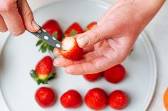 a person is cutting strawberries on a plate