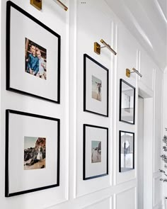 a white wall with black and white pictures hanging on it's sides, along with framed photos