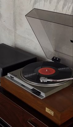 an old record player is sitting on top of a wooden table next to a wall