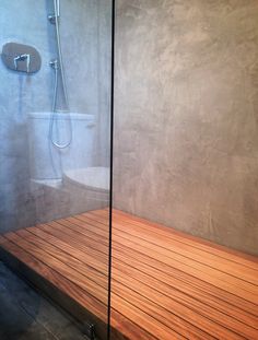 a bathroom with a glass shower door and wooden flooring on the side of it