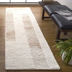 a large white rug in the middle of a living room next to a couch and window