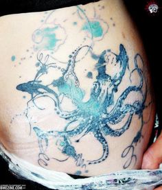 an octopus tattoo on the side of a woman's stomach, with blue ink