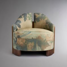 an upholstered chair with floral fabric and wood legs, on a gray background