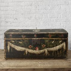 an old trunk sitting on top of a wooden table next to a white brick wall