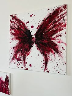 two paintings hang on the wall with red paint splattered all over them,