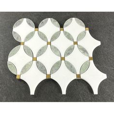 a white and gold mosaic tile with circles on the back side, set against a black background