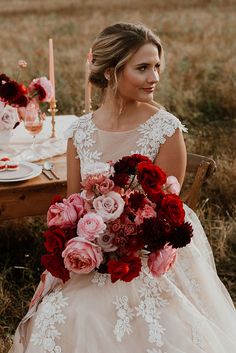 a woman in a wedding dress sitting at a table with a bouquet of flowers on it