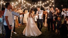 a bride and groom are walking through the grass with sparklers in front of them