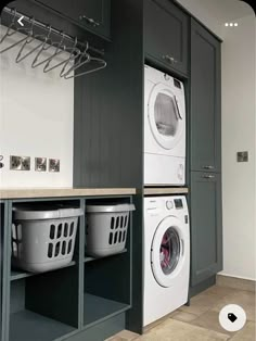 a washer and dryer in a laundry room next to cabinets with hanging hooks