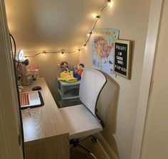 a room with a desk, chair and lights on the wall above it that is lit up