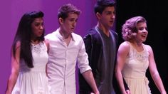 a group of young people standing next to each other in front of a purple background