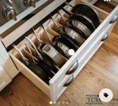 an open drawer with pots and pans in it