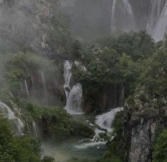 the waterfall is surrounded by lush green trees and foggy skies in the distance, as well as water cascading down the sides