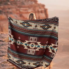 a woman wrapped in a blanket looking out at the desert