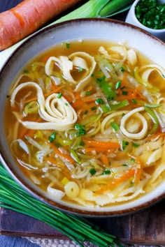 a bowl of soup with noodles, carrots and celery on the side