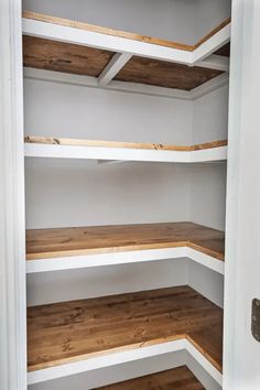 an empty pantry with white shelves and wood flooring on the bottom half of it