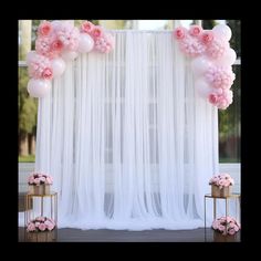 a white backdrop with pink flowers and balloons