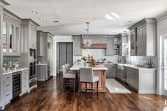 a large kitchen with wooden floors and gray cabinets