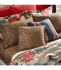 a leopard print bed spread with red pillows