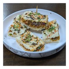 several pieces of food on a plate with toothpicks