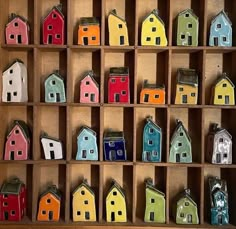 small colorful houses are in a wooden box on the wall, and there is also a keychain for each house