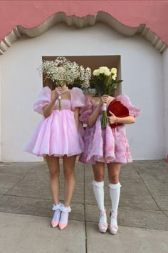 two girls in pink dresses holding flowers and posing for the camera