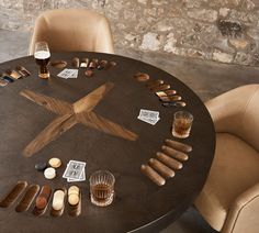 a round table topped with lots of different types of items next to glasses and bottles