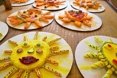 paper plates with painted faces on them are sitting on a table in front of children's artwork