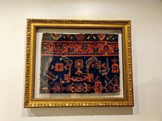 an old rug is hanging on the wall next to a gold framed frame with it's reflection