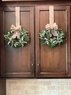 two wreaths are hanging on the cabinets