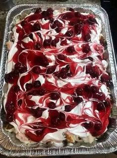 a cake with cherries and white frosting on it in a metal pan sitting on top of a table