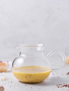 a glass pitcher filled with yellow liquid next to other ingredients on a white countertop