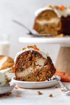 carrot cake with white frosting on a plate next to some carrots and a fork