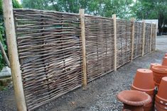 a fence made out of bamboo sticks and clay potted planters in front of it