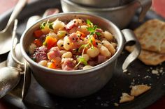 a bowl filled with food sitting on top of a plate next to crackers and utensils